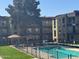 A view of a multi-story apartment building with a pool and barbeque area surrounded by green grass and trees at 461 W Holmes Ave # 277, Mesa, AZ 85210