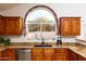 Kitchen featuring wooden cabinetry, granite countertops, stainless steel appliances, and an arched window at 5381 W Del Rio St, Chandler, AZ 85226