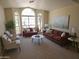 Bright living room with neutral carpet, modern sofas, decorative pillows, and large arched windows at 5381 W Del Rio St, Chandler, AZ 85226