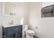 Bathroom features a white toilet, navy blue vanity with white countertop, mirror, and a window at 6915 S Sapphire Way, Chandler, AZ 85249