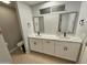 Modern bathroom featuring double sinks with white cabinets and stone countertops at 8227 N 47Th Dr, Glendale, AZ 85302