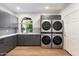 Modern laundry room with gray cabinets, stainless steel washer/dryer units, and a bright window at 9114 N 55Th St, Paradise Valley, AZ 85253