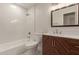 Bright bathroom with a modern vanity, stylish wood cabinet, and tiled shower/tub combo at 10135 W Orange Dr, Glendale, AZ 85307