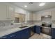 Modern kitchen with stainless steel appliances, white countertops, and contrasting blue cabinets at 10135 W Orange Dr, Glendale, AZ 85307