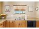 This kitchen features wood cabinetry, granite countertops, and a stainless steel double sink at 10848 W Crosby Dr, Sun City, AZ 85351