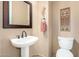 Neat powder room with pedestal sink, mirror, and toilet with classic neutral wall coloring at 11133 N 120Th Pl, Scottsdale, AZ 85259