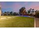 Expansive backyard with a pool, grass, mature trees, and privacy fencing at 1265 E La Fortuna Ct, San Tan Valley, AZ 85140