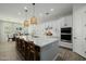 Bright kitchen with white cabinets, stainless steel appliances, large island with modern lighting, and wood-look tile floor at 1265 E La Fortuna Ct, San Tan Valley, AZ 85140