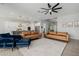 Open-concept living room with leather sofas, a ceiling fan, modern fireplace, and seamless flow to the kitchen at 1265 E La Fortuna Ct, San Tan Valley, AZ 85140