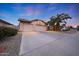 Charming home boasts a three car garage and meticulously kept desert landscaping at dusk at 12712 W Wilshire Dr, Avondale, AZ 85392