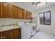 Functional laundry room equipped with a sink, washer, dryer, storage cabinets and a window at 130 E Jordon Ln, Phoenix, AZ 85086