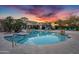 Community pool area with lounge chairs and tropical landscaping under a vibrant sunset at 16013 S Desert Foothills Pkwy # 2089, Phoenix, AZ 85048