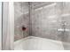 Bathroom showcasing a tub with marble-patterned tile surround, featuring a handheld shower head and red flower accent at 1635 W Dunbar Dr, Phoenix, AZ 85041