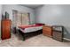 This bedroom includes a bed, wood dresser, mini fridge, window, and a gray walls at 1635 W Dunbar Dr, Phoenix, AZ 85041
