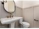 Stylish powder bathroom featuring a pedestal sink, round mirror, paneled walls, and sleek fixtures at 1645 E Minton St, Mesa, AZ 85203
