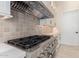 Close up of modern gas range and stainless hood and gray tile backsplash in new kitchen at 1645 E Minton St, Mesa, AZ 85203
