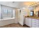 Bright bathroom featuring a soaking tub, glass block shower, and granite vanity with white cabinetry at 16532 W Rowel Rd, Surprise, AZ 85387