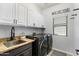 Well-organized laundry room with granite countertops, modern washer and dryer, and ample cabinet space at 16532 W Rowel Rd, Surprise, AZ 85387