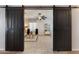 Stylish living room view through sliding barn doors with a ceiling fan and tile flooring at 16532 W Rowel Rd, Surprise, AZ 85387