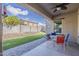Charming covered patio with outdoor dining area and a well-manicured artificial grass landscape at 16830 W Magnolia St, Goodyear, AZ 85338