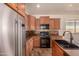 This kitchen features stainless steel appliances, brown wooden cabinets, an island, and tile floors at 18072 W Vogel Ave, Waddell, AZ 85355