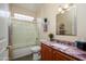 Bathroom featuring a glass shower/tub, wood cabinetry, decorative mirror, and marble countertop at 19140 N Tamarisk Flower Way, Surprise, AZ 85387