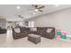 Bright living room features neutral walls, tile flooring, a ceiling fan, and a comfortable sectional at 21816 W Taft Ave, Wittmann, AZ 85361