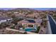 A stunning aerial view of a home, featuring a backyard pool, outdoor kitchen, desert landscape, and solar panels at 2224 N 83Rd Cir, Mesa, AZ 85207