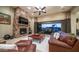 Comfortable living room featuring a stone fireplace, plush leather furniture, and seamless access to the outdoor patio at 2224 N 83Rd Cir, Mesa, AZ 85207