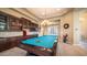 Elegant living space with a pool table, custom built-in bar, and tray ceiling with chandelier at 2224 N 83Rd Cir, Mesa, AZ 85207