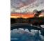 Stunning sunset reflecting on the clear pool water, showcasing the serene backyard ambiance and landscaping at 2224 N 83Rd Cir, Mesa, AZ 85207