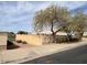 Exterior view of a property featuring a tan block wall and mature trees along the street at 24638 N 65Th Ave, Glendale, AZ 85310