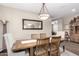 Warm dining area featuring a wooden table, modern chandelier, and seamless flow to the living room creating an inviting space at 36070 N Quiros Dr, San Tan Valley, AZ 85143