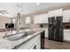 Kitchen island boasts granite counters, stainless steel sink and fixture, and modern cabinetry at 36070 N Quiros Dr, San Tan Valley, AZ 85143