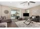 Comfortable living room with tile flooring, a ceiling fan, backyard access, and stylish, cozy furnishings at 36070 N Quiros Dr, San Tan Valley, AZ 85143