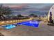 Backyard pool and hot tub with a stone deck, surrounded by manicured landscaping and a secure fence at dusk at 36070 N Quiros Dr, San Tan Valley, AZ 85143