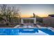 Inviting pool area with a modern fireplace, desert landscape, and mountain views at sunset at 37200 N Cave Creek Rd # 1035, Scottsdale, AZ 85262