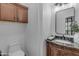 Stylish powder room with a granite countertop vanity, wood cabinets, and neutral walls at 3777 E Latham Ct, Gilbert, AZ 85297