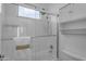 Clean, white bathroom featuring a shower with glass doors, tile surround, and functional storage shelves at 3777 E Latham Ct, Gilbert, AZ 85297