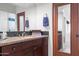 Bathroom with wood cabinets, granite countertops, black mosaic backsplash, and a large mirror at 41353 N 106Th St, Scottsdale, AZ 85262