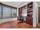 Office with custom shelving, desk, a large window with shades, and wood flooring at 41353 N 106Th St, Scottsdale, AZ 85262