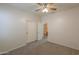 Inviting bedroom with closet, ceiling fan, carpet flooring, and a partial bathroom view at 44125 W Cydnee Dr, Maricopa, AZ 85138