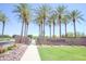 Landscaped community entrance with lush palm trees, desert plants, and attractive signage on a sunny day at 44125 W Cydnee Dr, Maricopa, AZ 85138