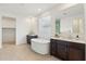 Bright bathroom featuring dual vanities, freestanding tub, walk-in shower with tiled walls, and wood-look tile flooring at 5046 W Karl St, San Tan Valley, AZ 85144