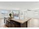 A kitchen features an island with a farmhouse sink, granite countertop, dark cabinets, and a view of the great room at 5046 W Karl St, San Tan Valley, AZ 85144
