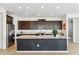 A kitchen features dark cabinets, stainless steel appliances, a large island, and wood-look tile floors at 5046 W Karl St, San Tan Valley, AZ 85144