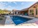 Backyard featuring a pool with a safety net, an outdoor kitchen under pergola, patio, and desert landscaping at 5215 S Monte Vista St, Chandler, AZ 85249