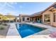Backyard featuring a pool with safety net, an outdoor kitchen under pergola, patio, and desert landscaping at 5215 S Monte Vista St, Chandler, AZ 85249