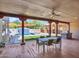 Covered patio with dining area, built-in grill, and views of the pool and waterfall feature at 5805 E Agave Pl, Carefree, AZ 85377