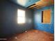 Depicts a blue bedroom featuring boarded up windows, damaged drywall and ceiling, and worn flooring at 6408 S 10Th St, Phoenix, AZ 85042